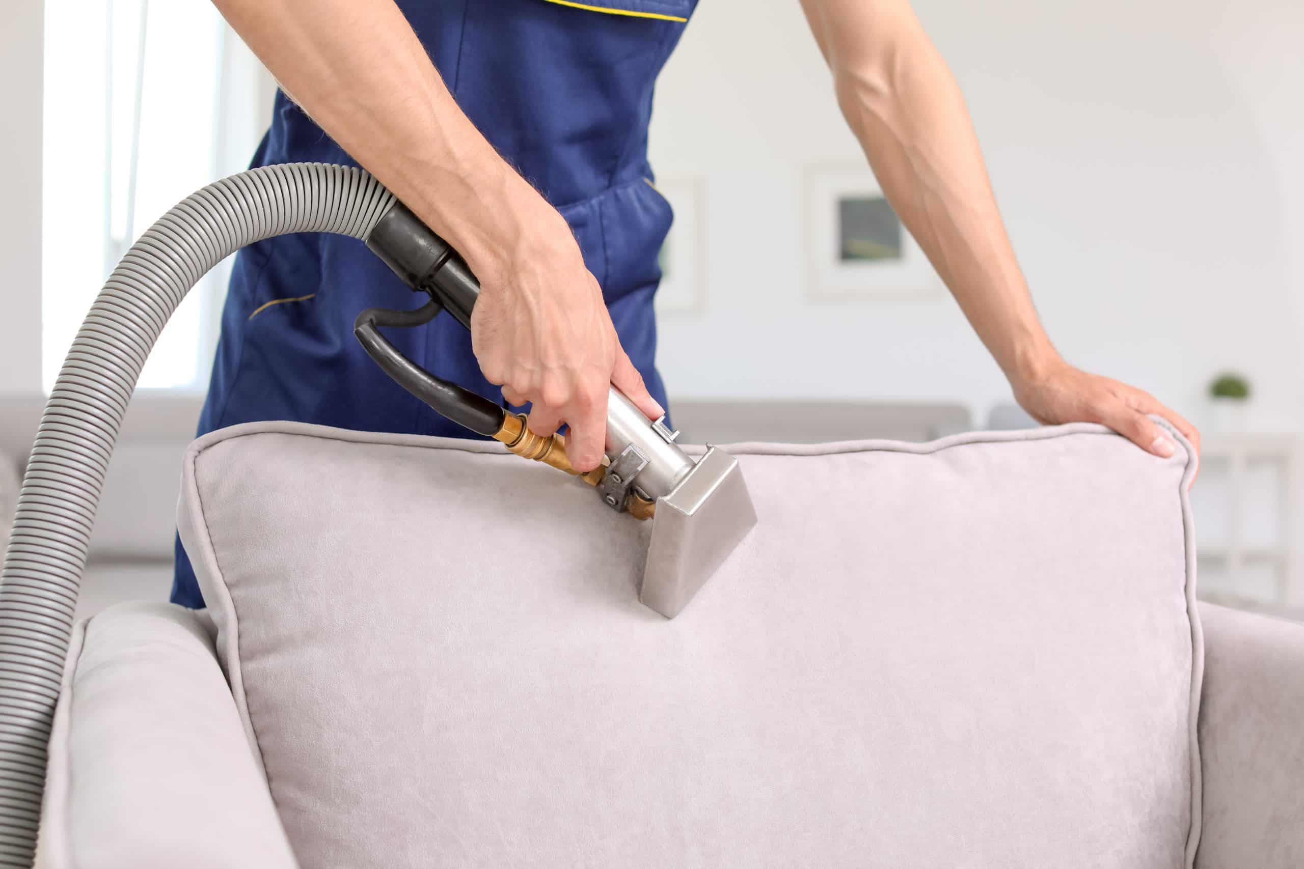 Dry cleaning worker removing dirt from armchair indoors